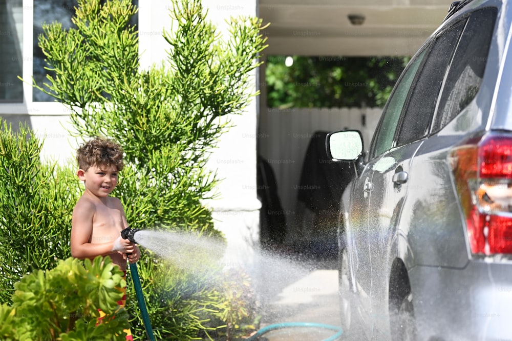 a young boy is playing with a water hose