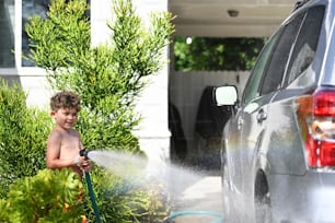 a young boy is playing with a water hose