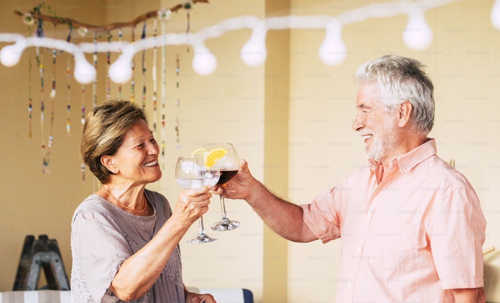 Happy old senior caucasian couple celebrate together with a cup of wine - people having fun celebrationth drinks - retired elderly joy lifestyle - end coronavirus emergency