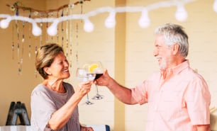 Happy old senior caucasian couple celebrate together with a cup of wine - people having fun celebrationth drinks - retired elderly joy lifestyle - end coronavirus emergency