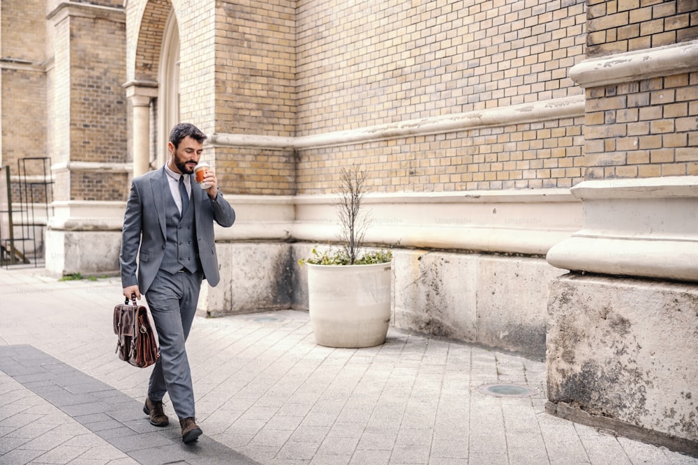 Full length of handsome businessman drinking coffee from disposable cup and going to work.