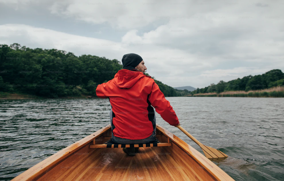 Rear view of man paddling canoe on the lake. Rainy day boat ride. photo ...
