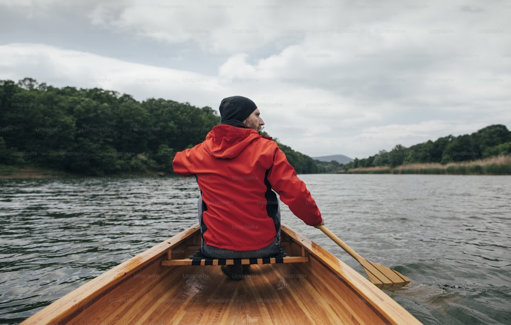 Vue arrière d’un homme pagayant en canoë sur le lac. Promenade en bateau les jours de pluie.