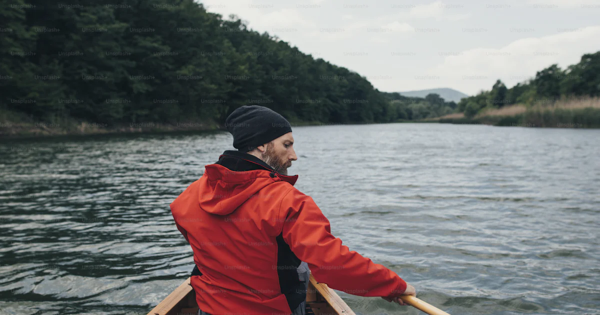 Rear view of man paddling canoe on the lake. Rainy day boat ride. photo ...