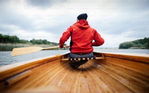 Vista posteriore dell'uomo che rema in canoa sul lago. Giro in barca in un giorno di pioggia.