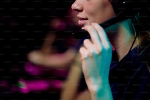 Close-up of young woman playing network video game and speaking into microphone of headset while discussing game strategy with team member