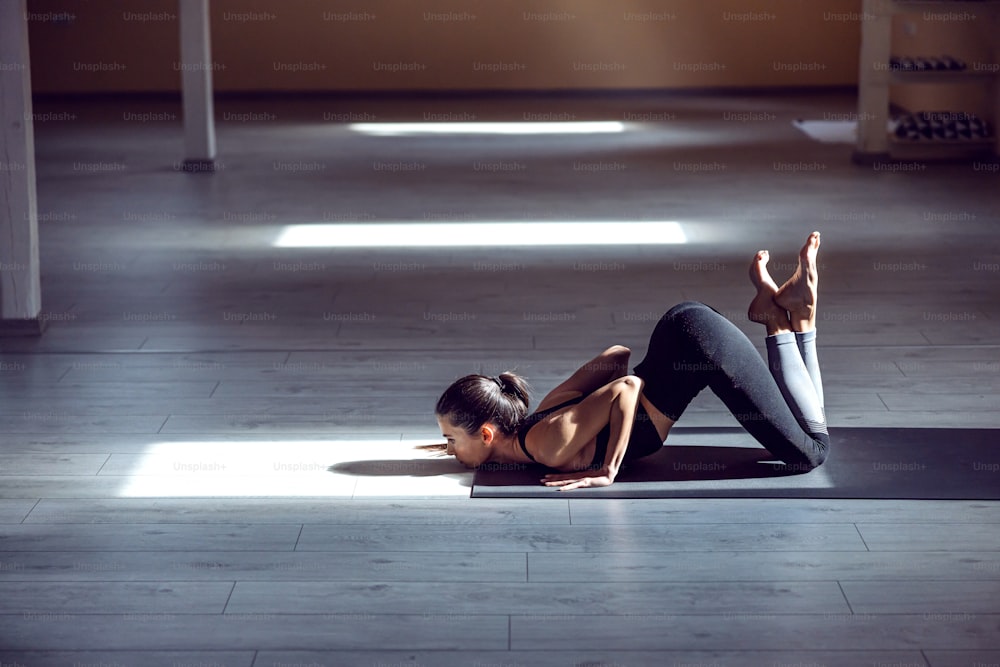 Giovane ragazza yogi magra attraente dedicata in posizione yoga a otto punti. Interno dello studio di yoga.