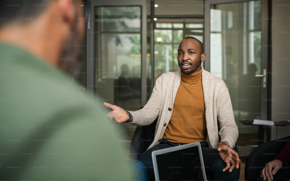 Giovane uomo d'affari afroamericano che parla con un gruppo eterogeneo di colleghi durante una riunione in un ufficio