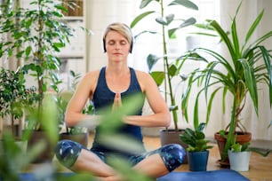 Front view of young woman indoors at home, doing yoga exercise. Copy space.