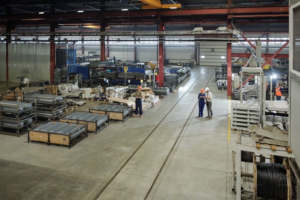 Funcionários em capacetes trabalhando na loja da fábrica moderna na produção de tanques de ar