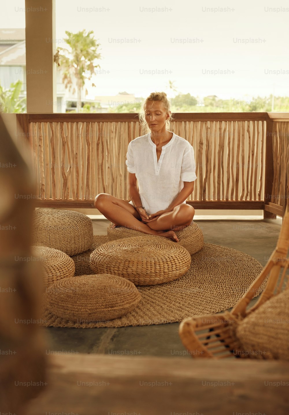 Meditación. Meditar para un estilo de vida saludable. Práctica de yoga en casa para la relajación y el equilibrio mental. Mujer Madura Sentada En Asiento Bajo En Pose De Loto En La Terraza.