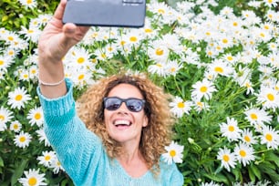 Glück und fröhliche Menschen mit schönen erwachsenen Frauen, die die Arme öffnen und den natürlichen und Blumenhintergrund im Park genießen - weibliches kaukasisches Lächeln und Spaß haben - glückliches Leben und Freiheitskonzept