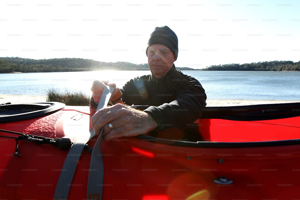 a man sitting in a red canoe on a sunny day
