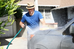 Um homem está lavando seu carro com uma mangueira