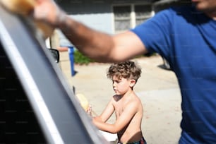 a young boy getting food out of the back of a car