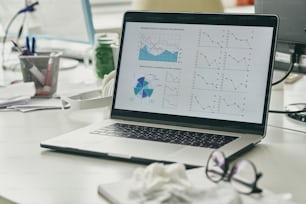 Financial graphs and diagram on display of laptop on workplace of contemporary broker or banker that is absent in the moment