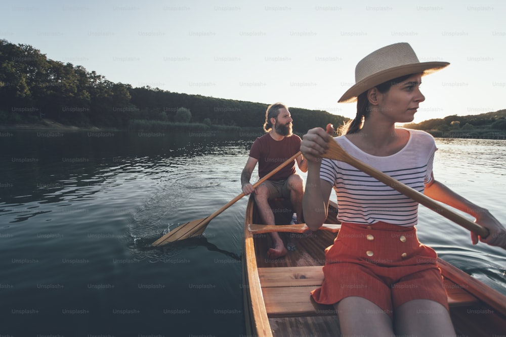 夕日湖でカヌーを漕ぐカップル。のんびりとボートに乗る女性と男性。