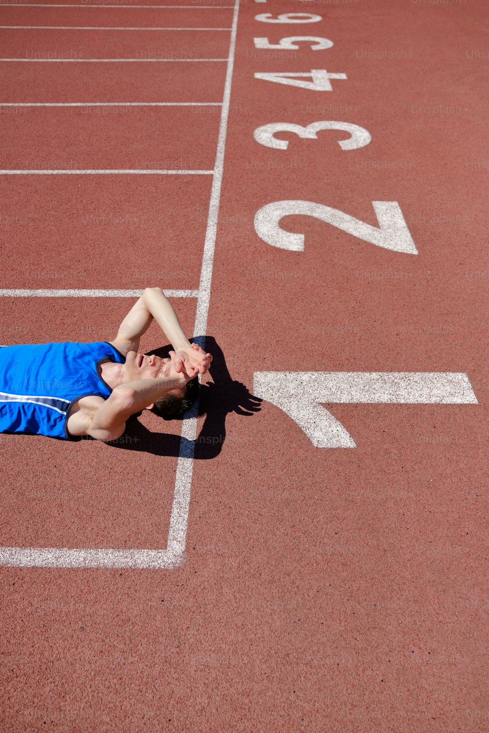 Portrait of sportsman laying tired on running track at the stadium on sunny summer day. Real bodies, try again, diversity, recovery, failure concept