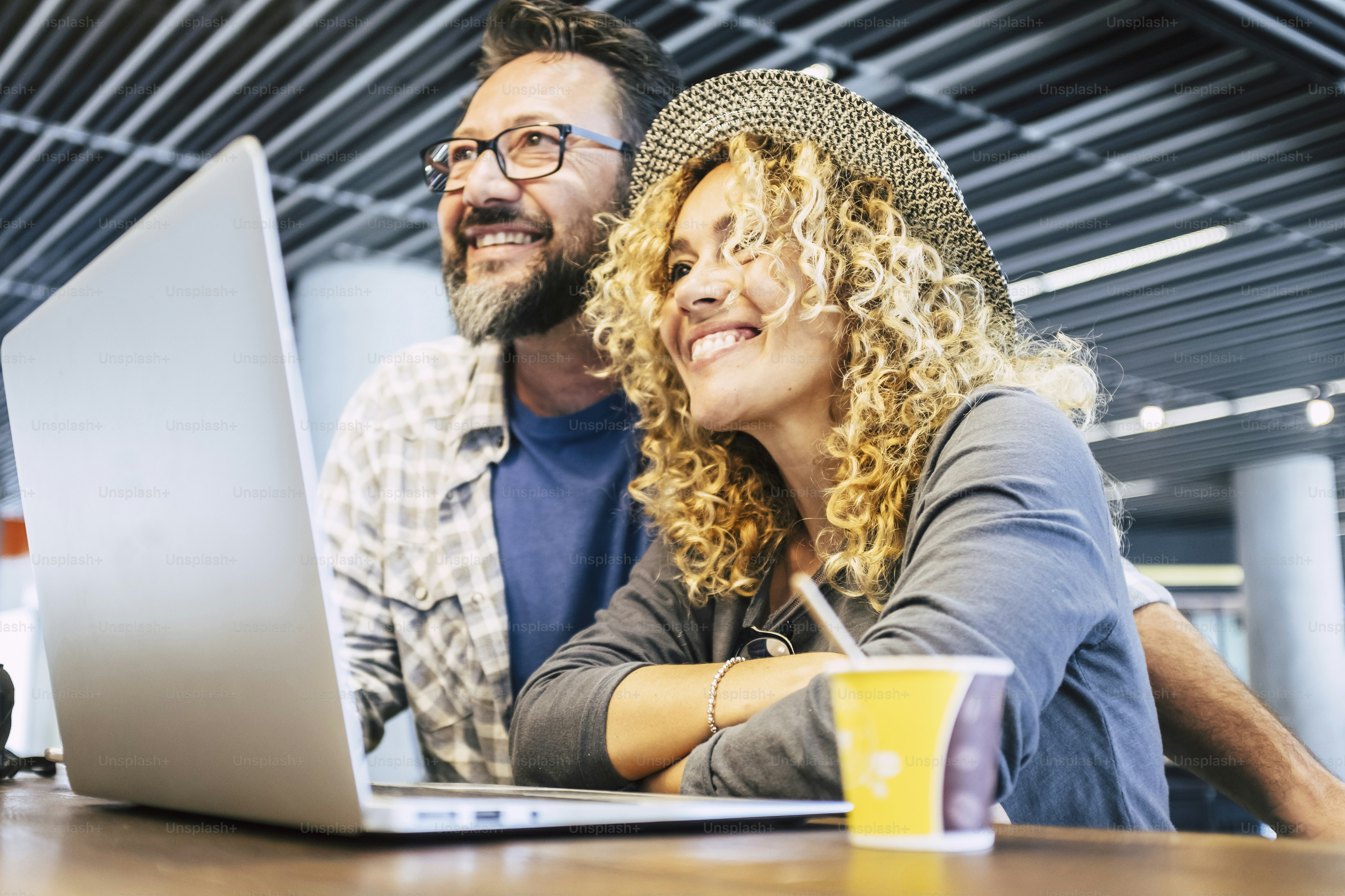 Happy and cheerful people couple of modern young adult worker with technology laptop compter - connected lifestyle and digital nomad office - smart working everywhere travel trendy life for woman and man