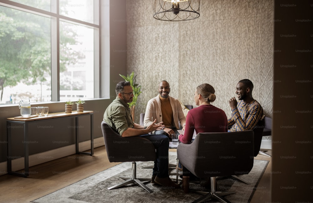 Diverse group of businesspeople smiling and talking together during a casual meeting in an office lounge area