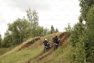 Rear view of extreme motorcyclists in helmets reaching speed while climbing hill on rough road