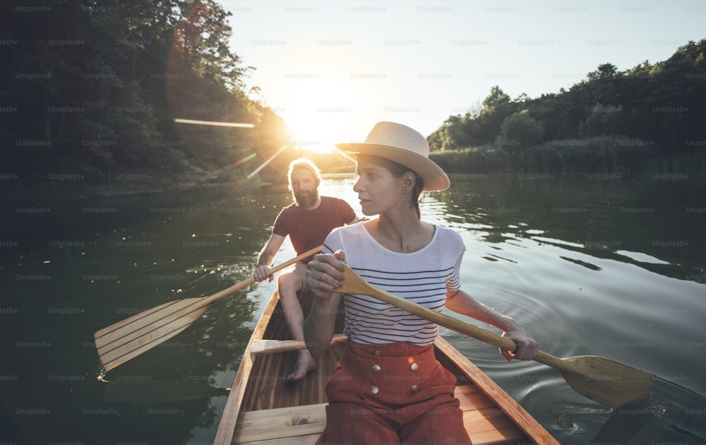 La pareja disfruta remando en canoa en el lago al atardecer. Mujer y hombre en un tranquilo paseo en barco.
