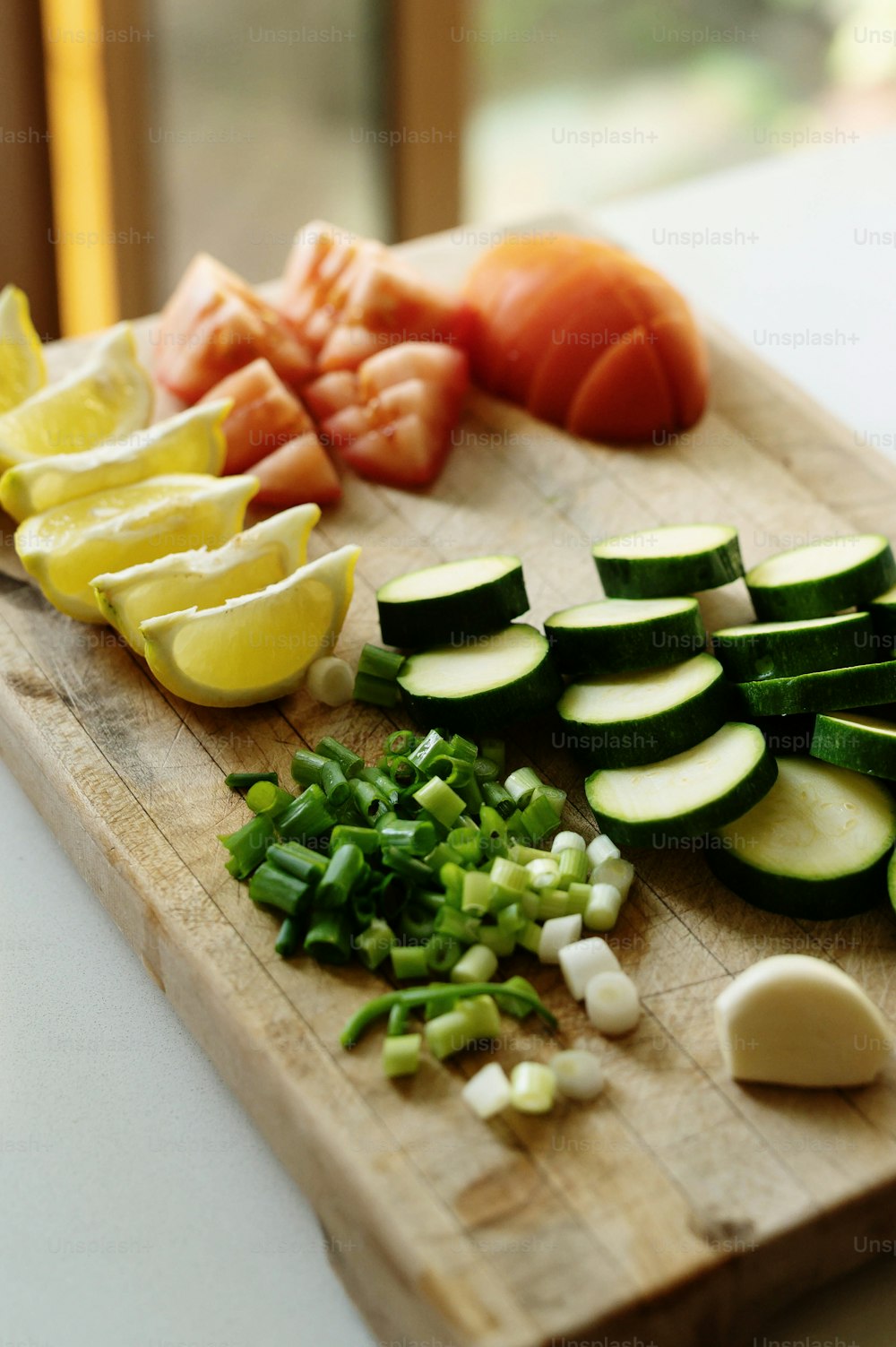 A cutting board with chopped vegetables including tomatoes, zucchini and lemon