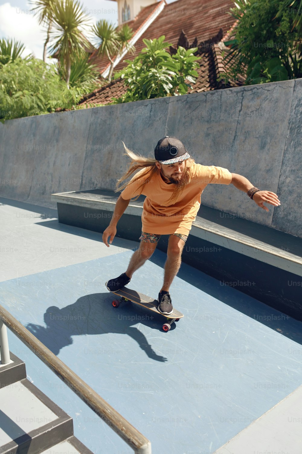 Subcultura. Homem skatista no Skatepark. Cara em traje casual com equipamento esportivo moderno andando de skate em rampa de concreto. Atividade extrema como estilo de vida urbano.