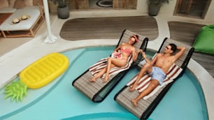 Man And Woman At Pool. Top View Of Couple In Love Enjoying Summer Vacation At Tropical Villa. Handsome Guy And Beautiful Girl Chilling On Poolside. Honeymoon At Luxury Cottage.