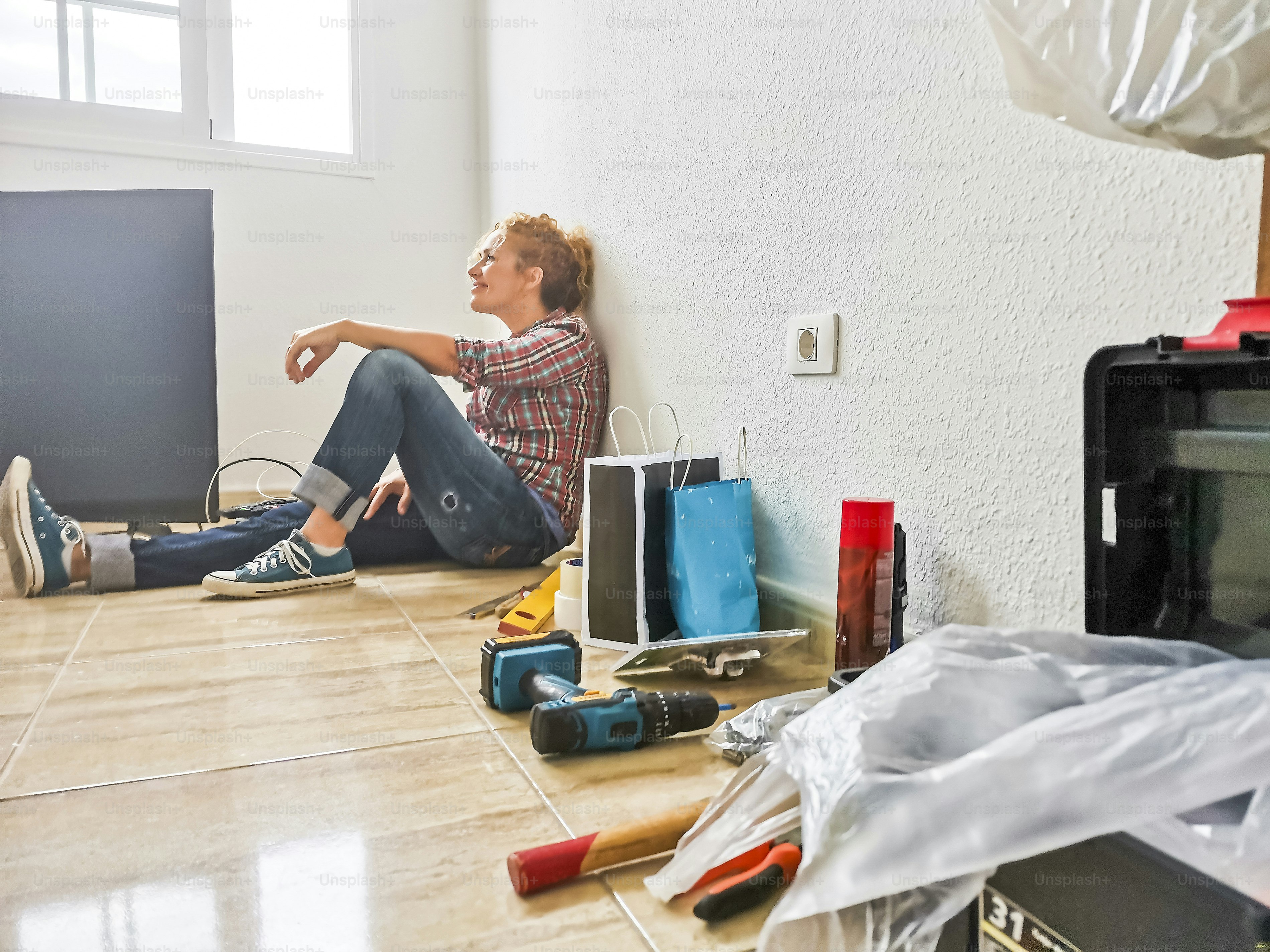Happy and tired woman rest on the floor after home works during a mortgage - new house and life concept - people enjoy change and diy jobs - independence concept for female