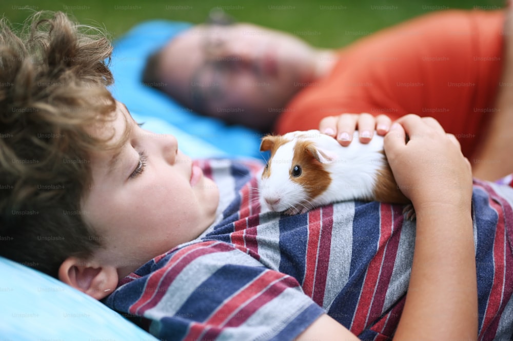 um menino deitado em uma cama com um hamster no colo