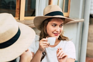 Cheerful beautiful young woman portrait drinking coffee at the bar with friend - date and outdoor leisure activity for people and friendship - cafe store and pretty female
