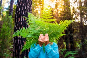 자연 숲에서 큰 잎으로 숨겨진 알아볼 수 없는 사람들의 초상화 - 지구의 날과 자연 야외 환경 레저 활동의 개념 - 삼림 벌채가 없고 지구 생활 방식을 구하십시오.
