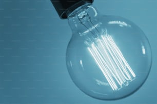 Vintage light bulb on blue background, close up. Glowing edison bulb