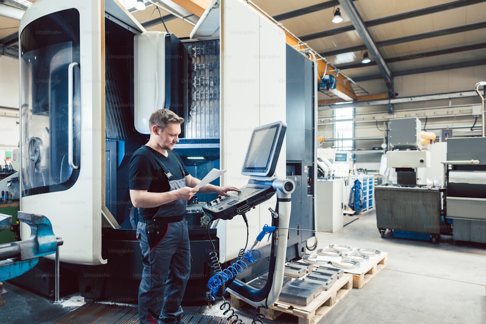 Worker in metal industry operating a modern cnc lathe