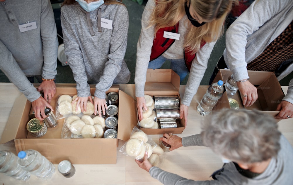 Vue de dessus d’un groupe de bénévoles travaillant dans un centre de dons de charité communautaire, une banque alimentaire et un concept de coronavirus.