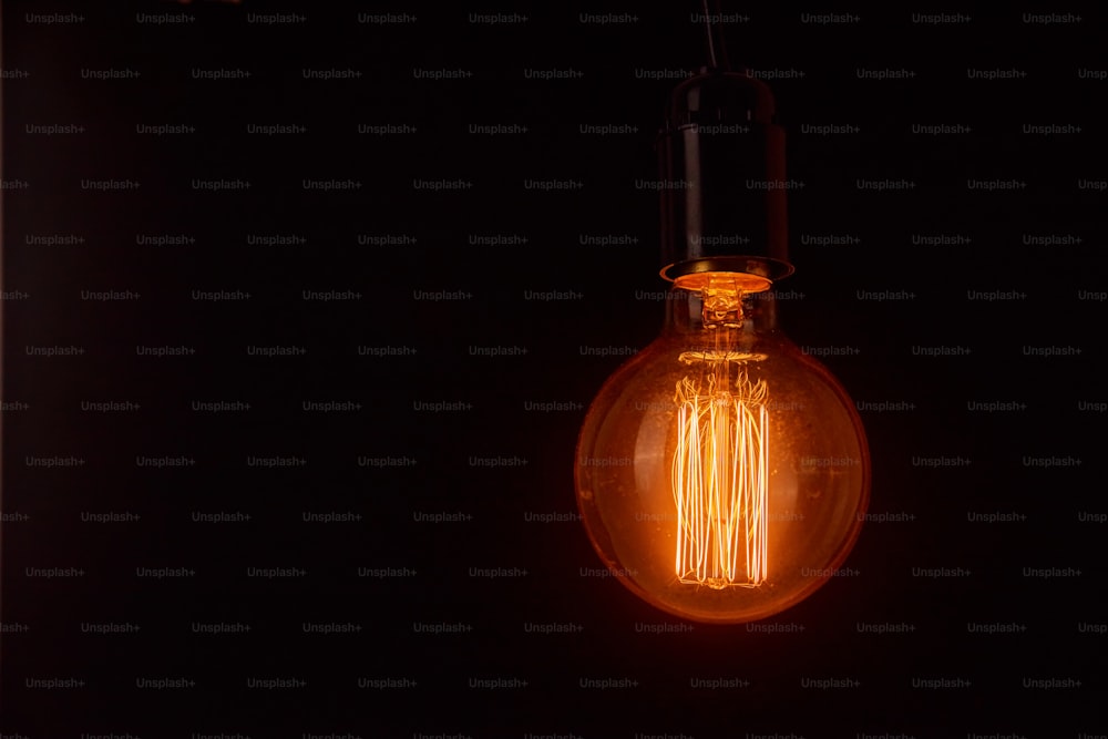 Vintage light bulb on black background with copy space. Glowing edison bulb