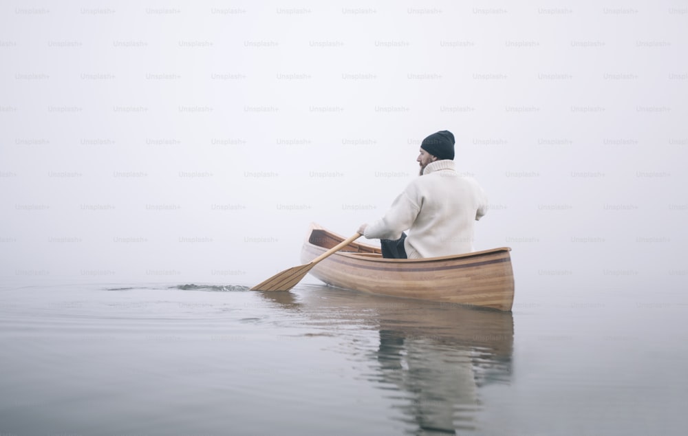 Rear view of man paddling canoe in the winter, copy space.