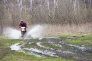 田舎道を移動しながら泥道でレースをするモトクロスライダー