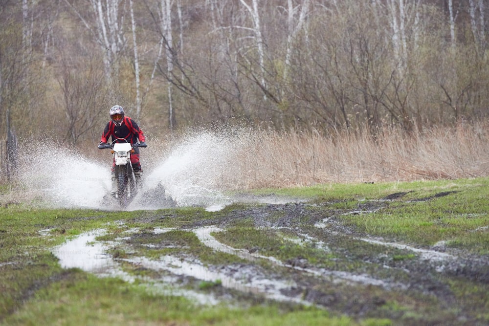Motorcross rider racing in mud track while moving down country road