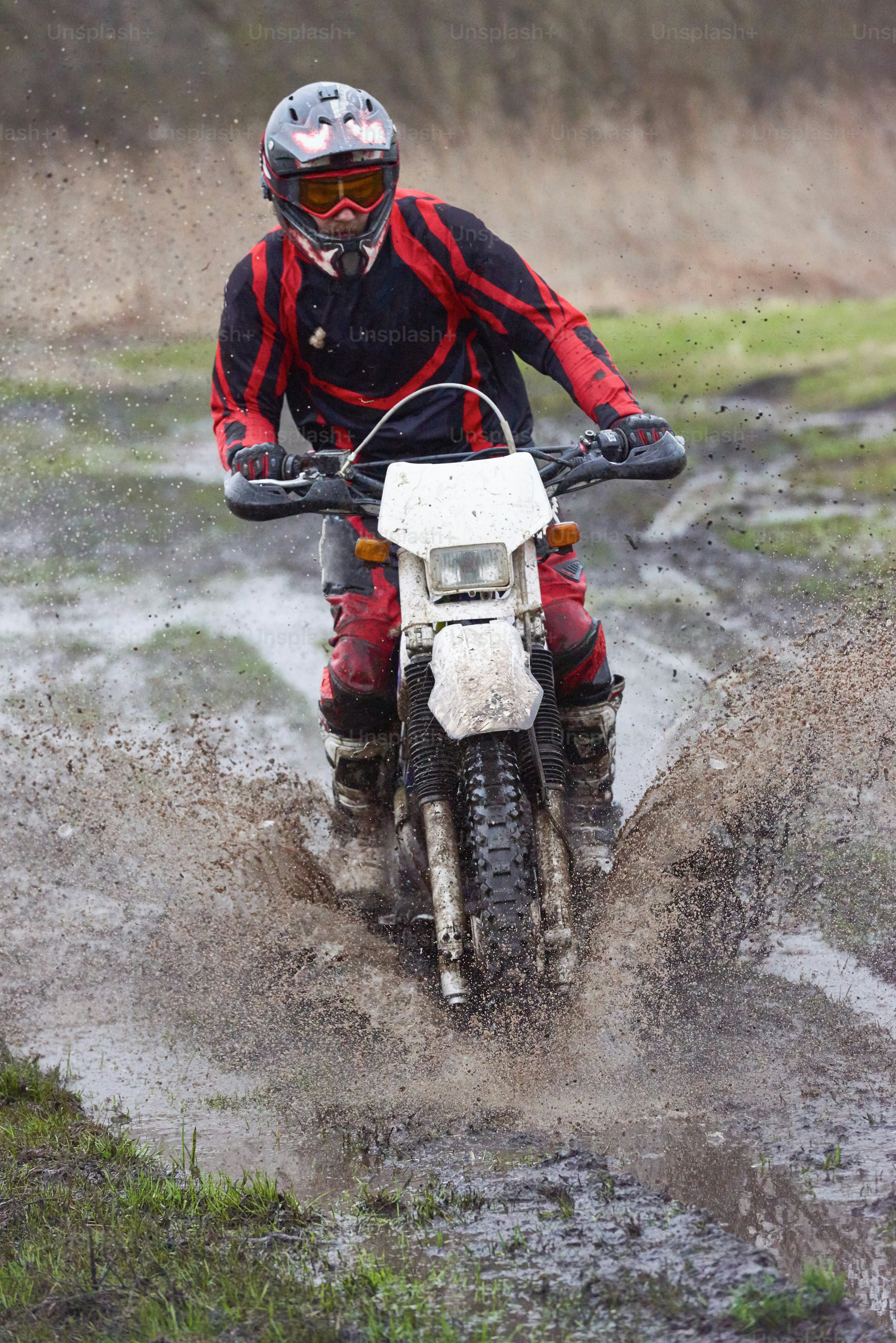 Extreme racing on mud track with male professional riding in dirty puddle