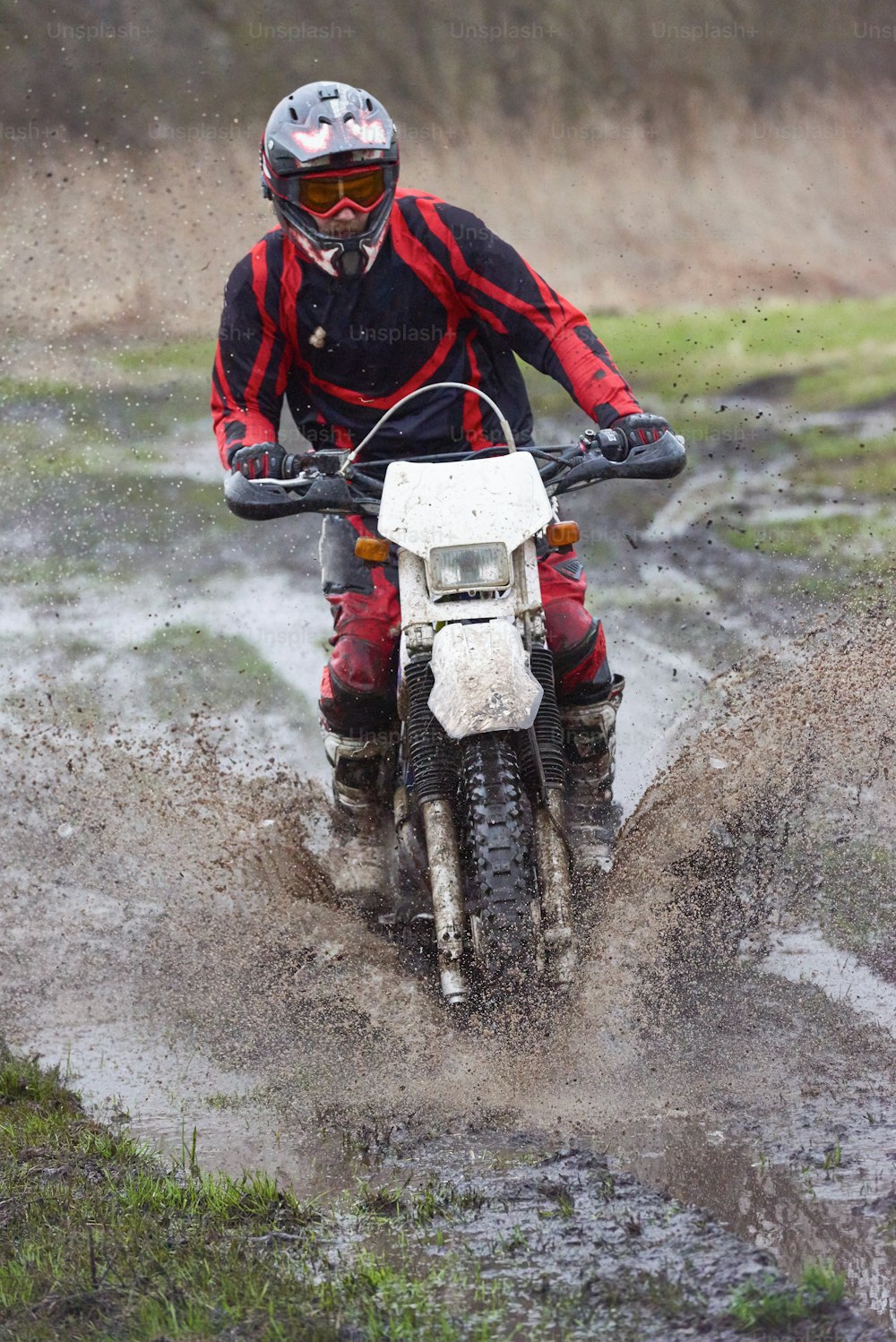 Extreme racing on mud track with male professional riding in dirty puddle