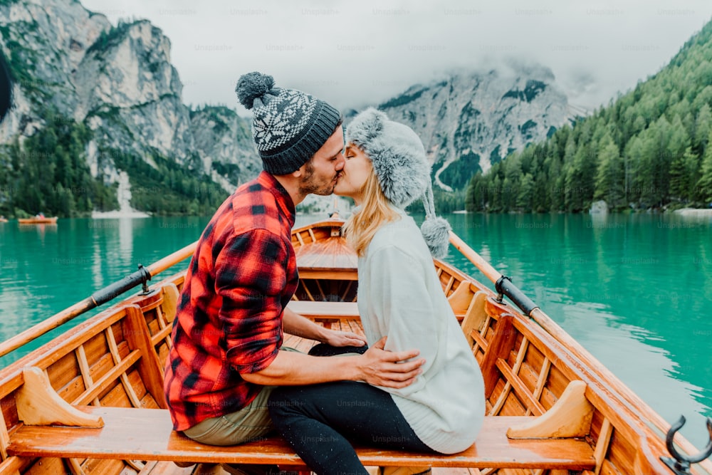 Braies 이탈리아의 고산 호수를 방문하는 두 명의 성인의 낭만적 인 키스. 사랑에 빠진 관광객은 가을 산에서 함께 사랑의 순간을 보냅니다. 커플, 방랑벽 및 여행 개념.