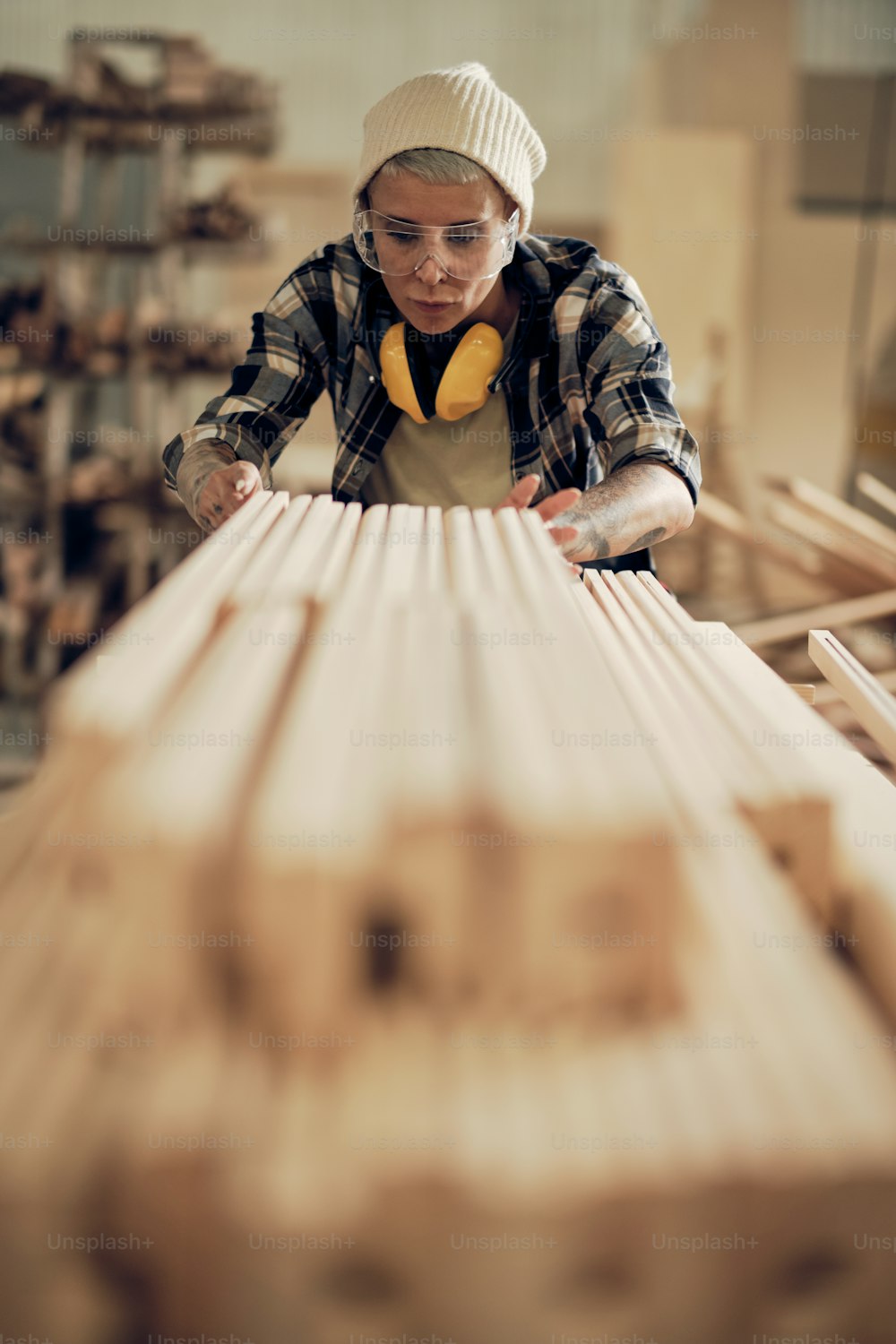 Retrato de carpintera fuerte que trabaja con madera, apilando y nivelando madera en pila