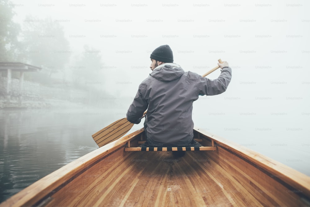 Vista traseira do homem remando canoa na neblina.