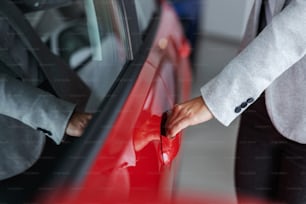 Primo piano del venditore di auto femminile che apre la portiera dell'auto mentre si trova nel salone dell'auto.