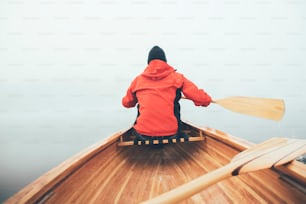 Rear view of man paddling canoe in the winter.