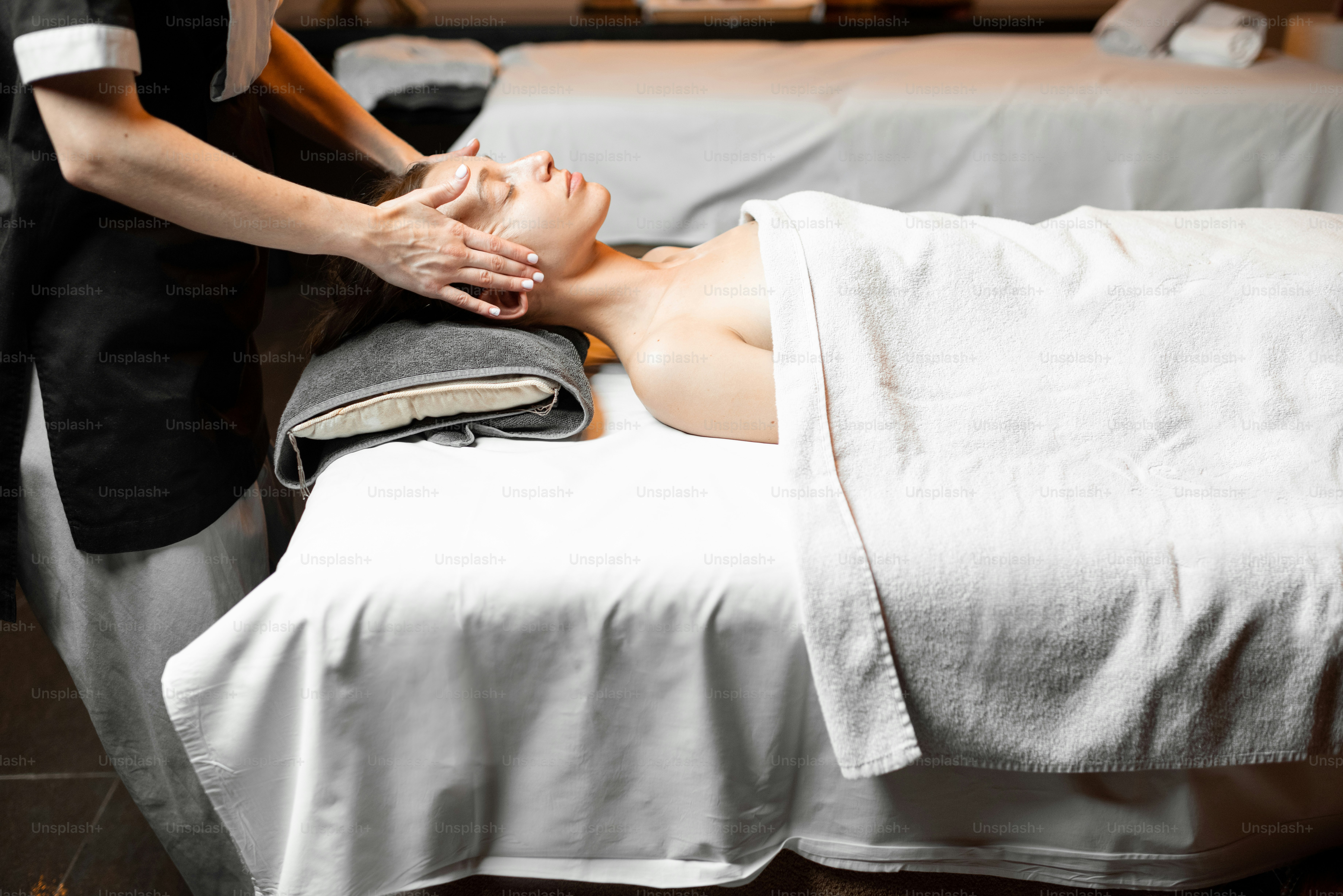 Wanita muda menerima pijatan wajah, bersantai di salon Spa