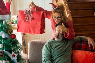 Christmas time and holiday season concept with happy people couple at home in surprise and gift presents exchange - happiness and joyful with woman and man in love and relationship together