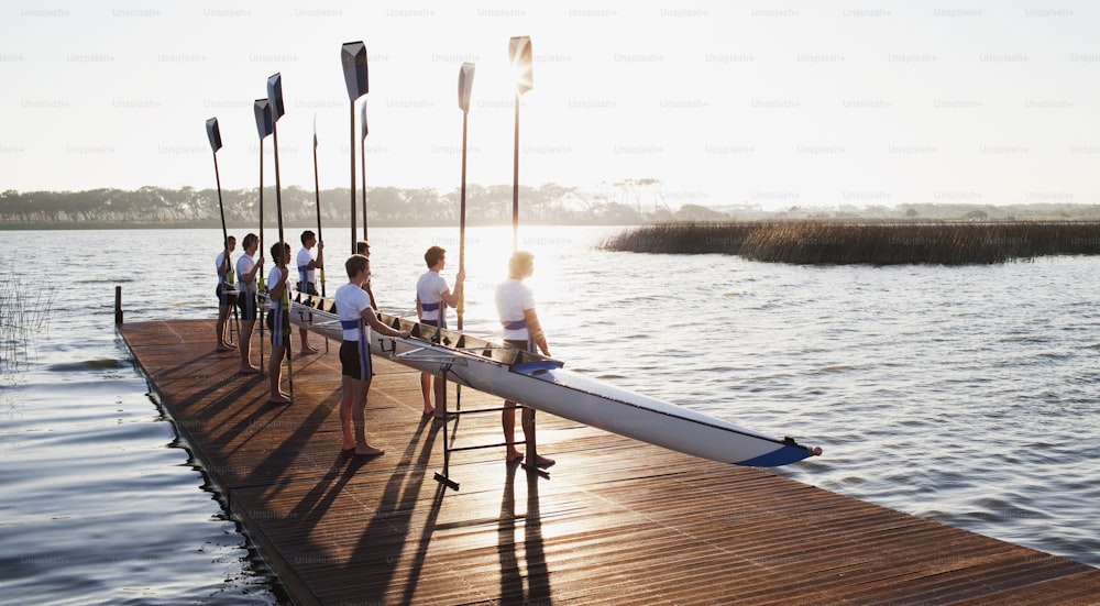 a group of people standing on a dock next to a body of water